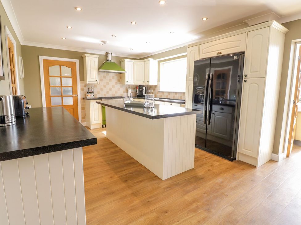 A kitchen with an island and a refrigerator at Ger Y Mor in Cemaes Bay