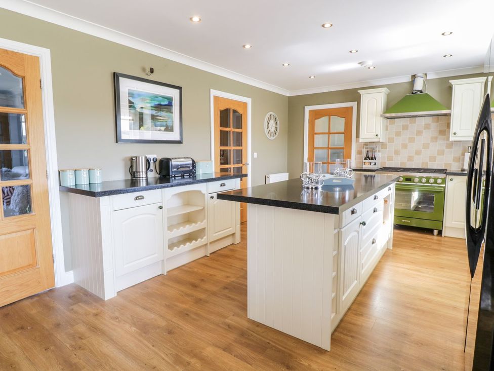 A kitchen with an island and appliances at Ger Y Mor Cemaes Bay