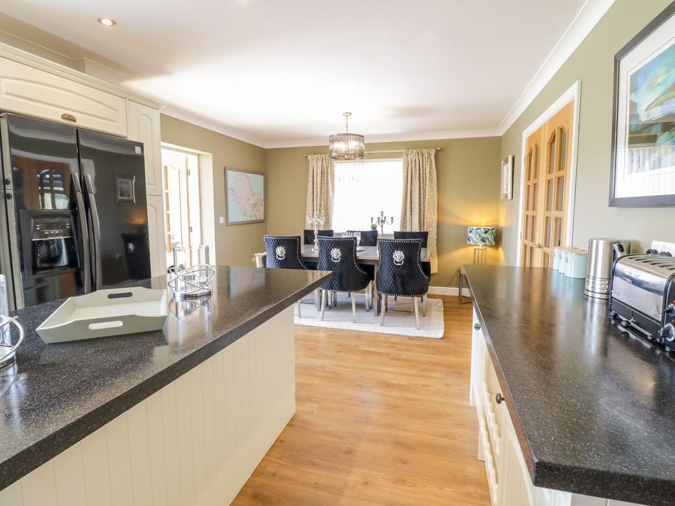 A kitchen with a dining area and refrigerator at Ger Y Mor in Cemaes Bay