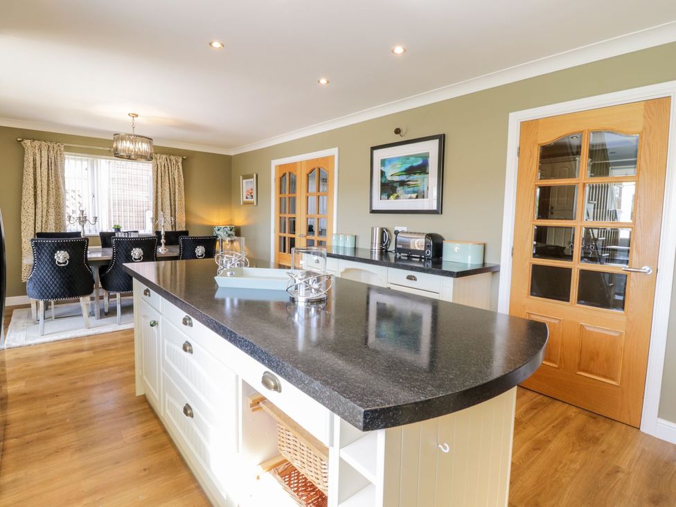 A kitchen with an island and dining table at Ger Y Mor in Cemaes Bay