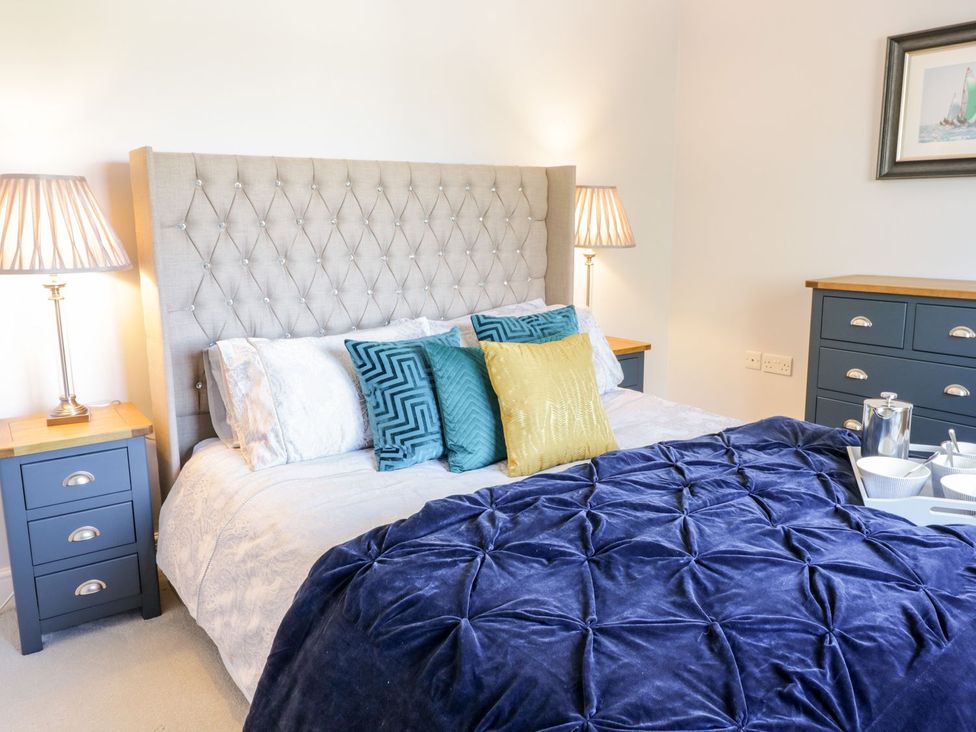 A bedroom with a bed, nightstand, lamp, and chest of drawers at Ger Y Mor Cemaes Bay