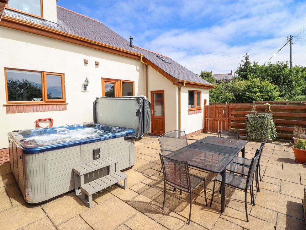 An outdoor area with a hot tub and a dining set at Ger Y Mor, Cemaes Bay