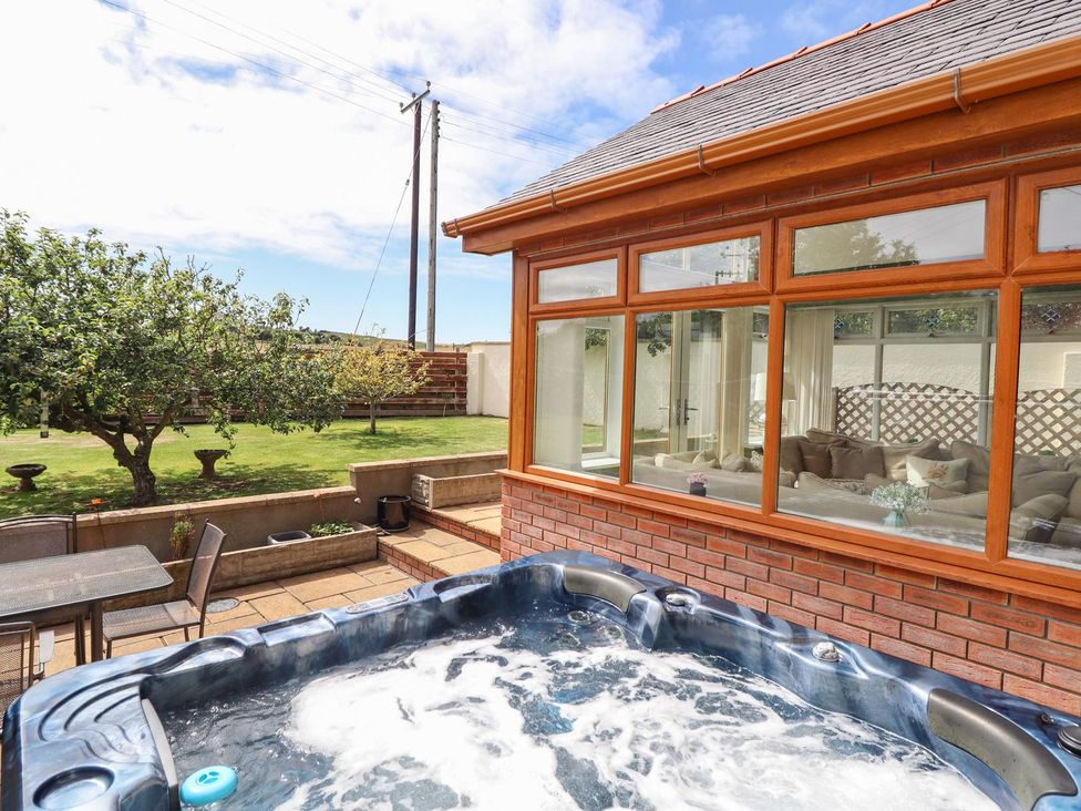 A hot tub and seating area in the garden at Ger Y Mor in Cemaes Bay