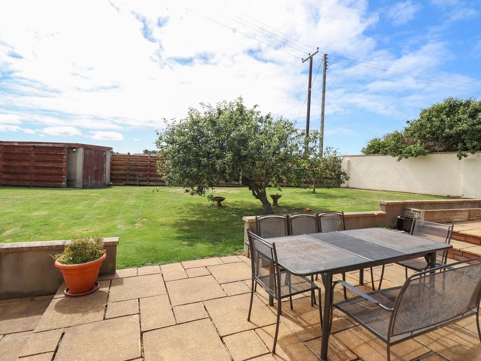 A garden with a dining table and chairs at Ger Y Mor in Cemaes Bay