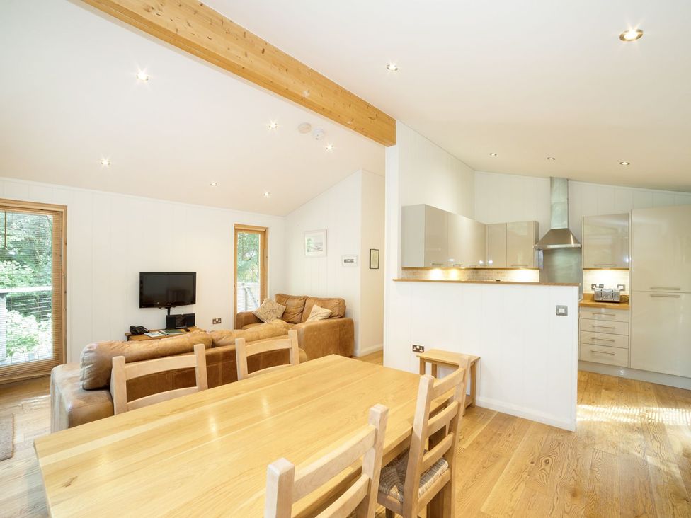 A living room with a sofa and dining area at 5 Tree Tops in Liskeard