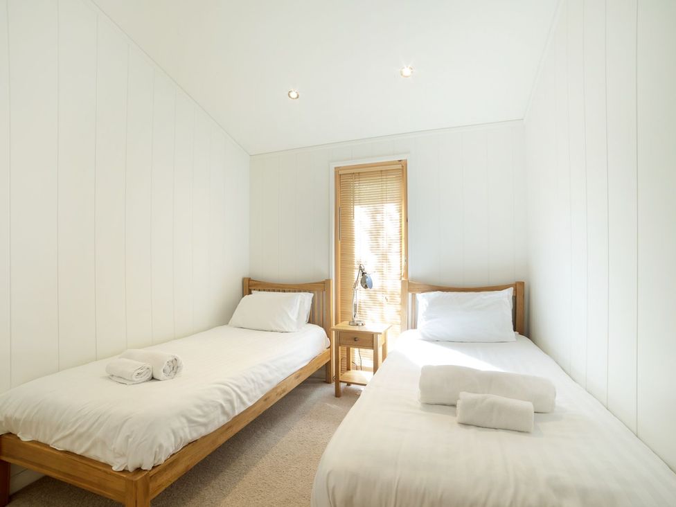 A bedroom with two single beds and a lamp on the table at 5 Tree Tops in Liskeard