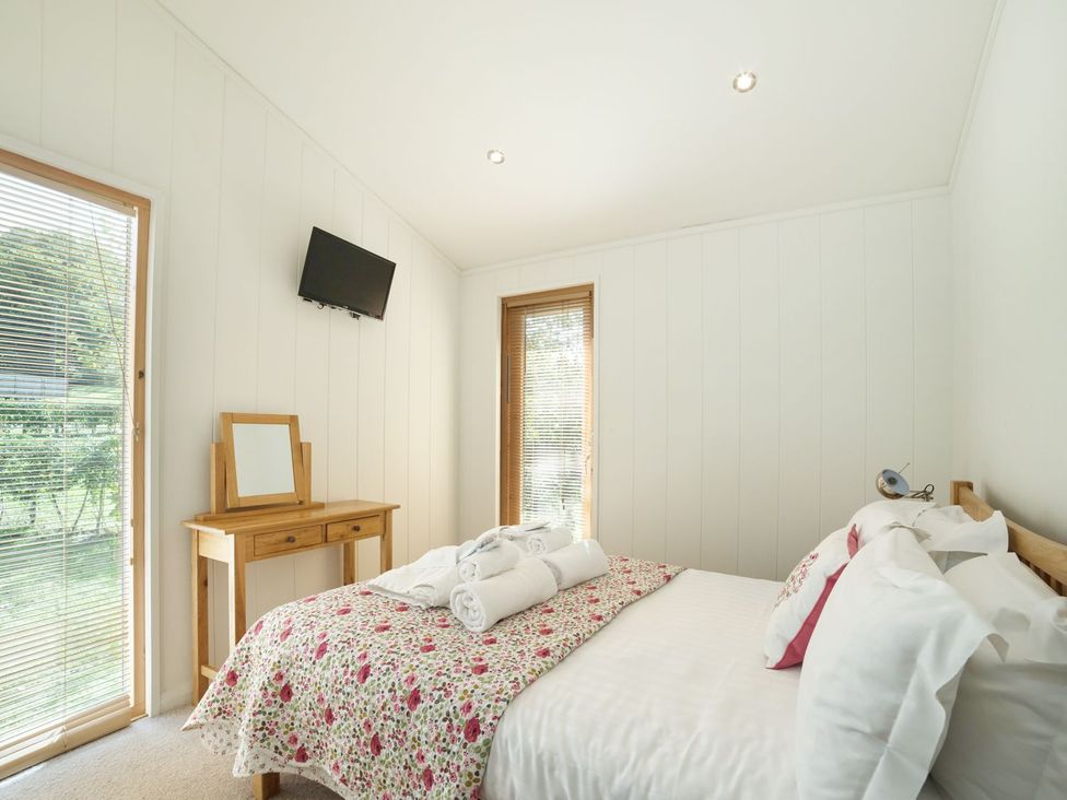 A bedroom with a bed, table and television at 5 Tree Tops in Liskeard