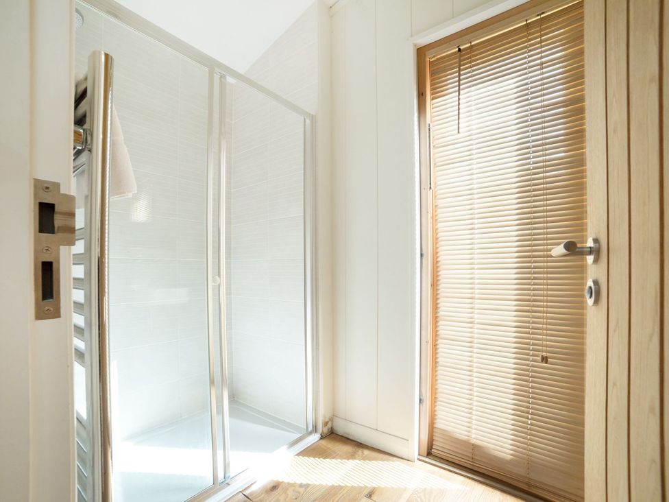 A bathroom with a shower and wooden door at 5 Tree Tops Liskeard