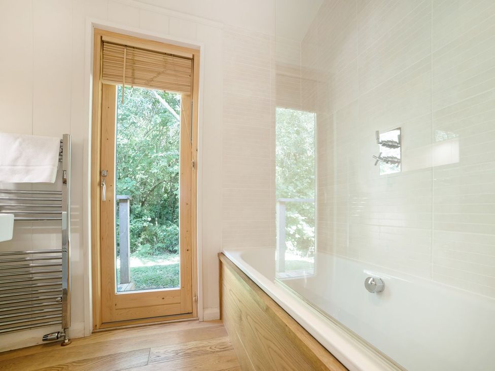 A bathroom with a bathtub and a door leading outside at 5 Tree Tops Liskeard