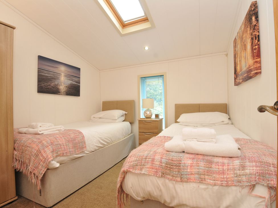 A bedroom with two beds and a nightstand at 5 Tree Tops in Dobwalls