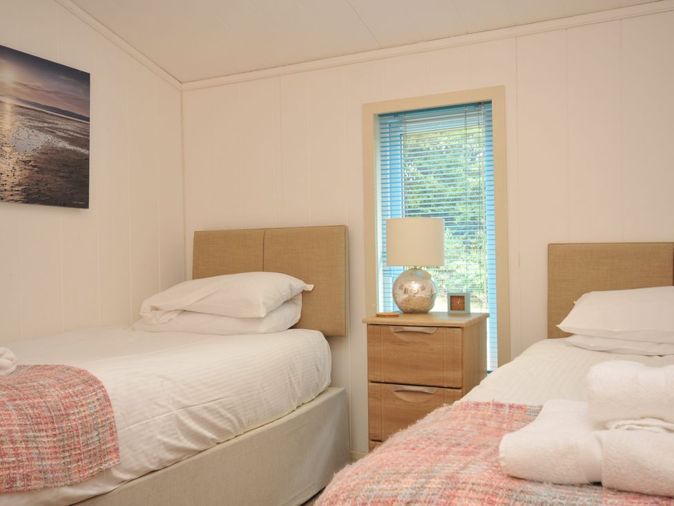 A bedroom with two beds and a lamp on a bedside table at 5 Tree Tops in Dobwalls