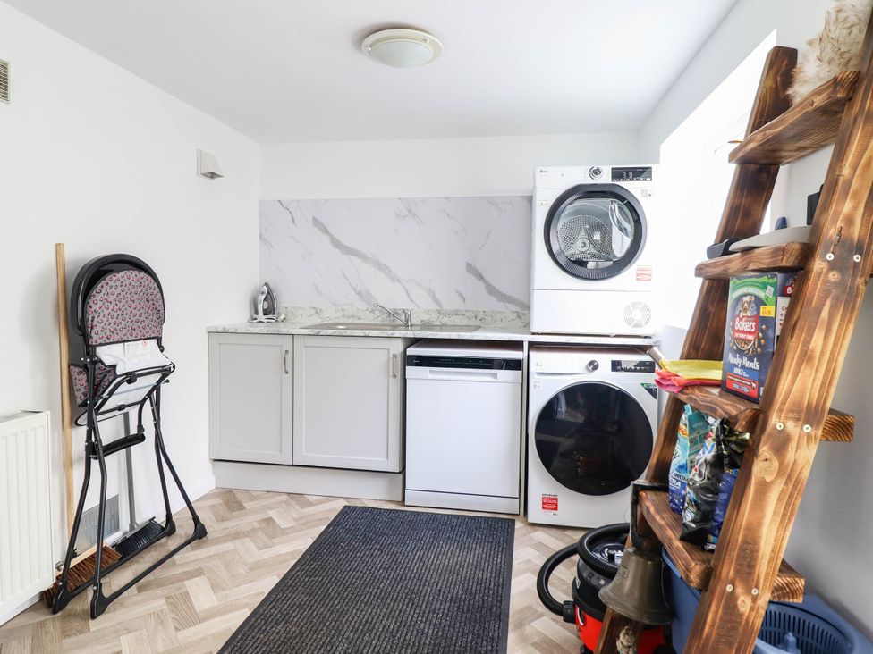 A laundry room with appliances and a high chair at 1 Glanaber Terrace