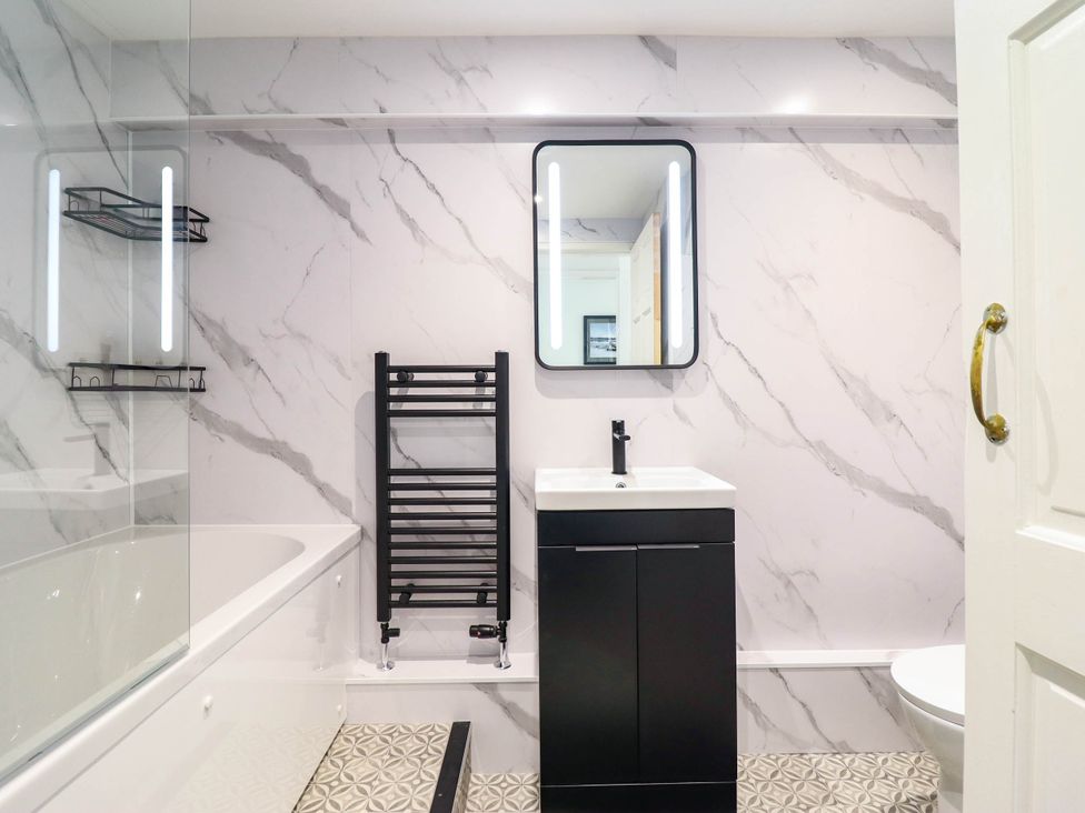 A bathroom with a bathtub, sink, and towel rail at 1 Glanaber Terrace