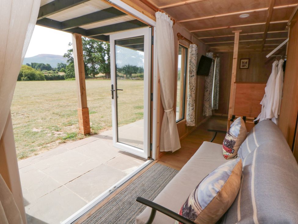 A living room with a sofa and a door leading to a garden at Oak Lodge in Brecon
