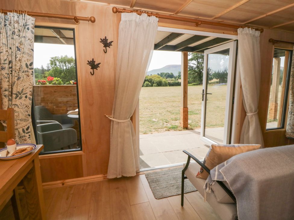 A living room with a view of a patio and garden at Oak Lodge in Brecon