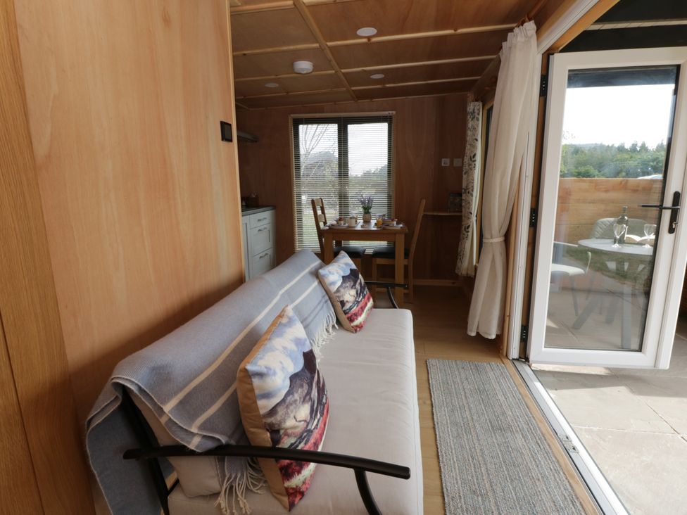 A living room with a sofa and dining area at Oak Lodge in Brecon