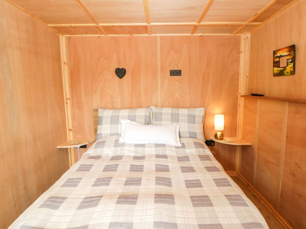 A bedroom with a bed and bedside table at Oak Lodge in Brecon