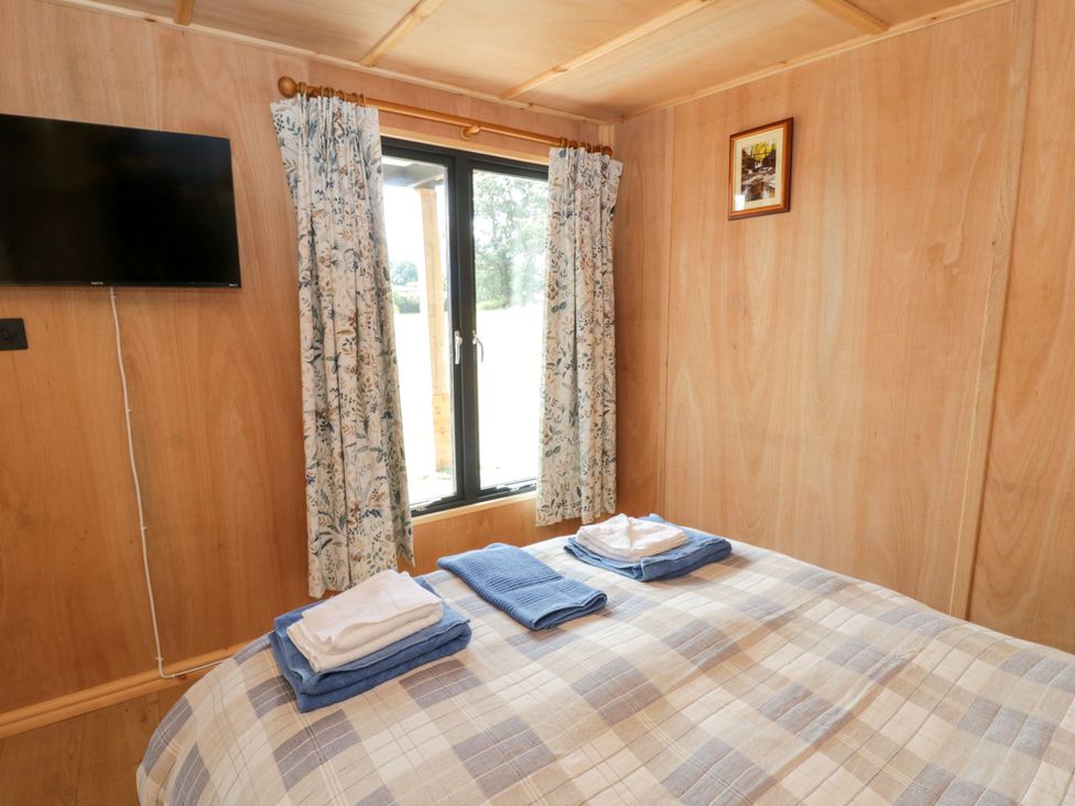 A bedroom with a bed and a TV at Oak Lodge in Brecon