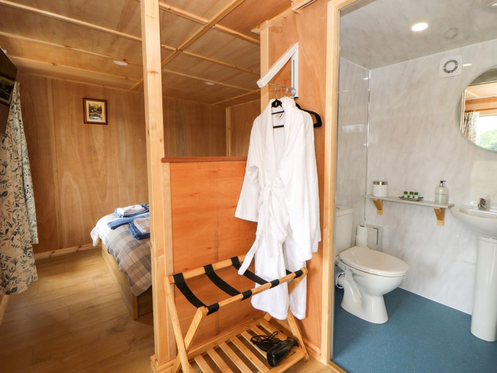 A bathroom with a robe and towels at Oak Lodge in Brecon