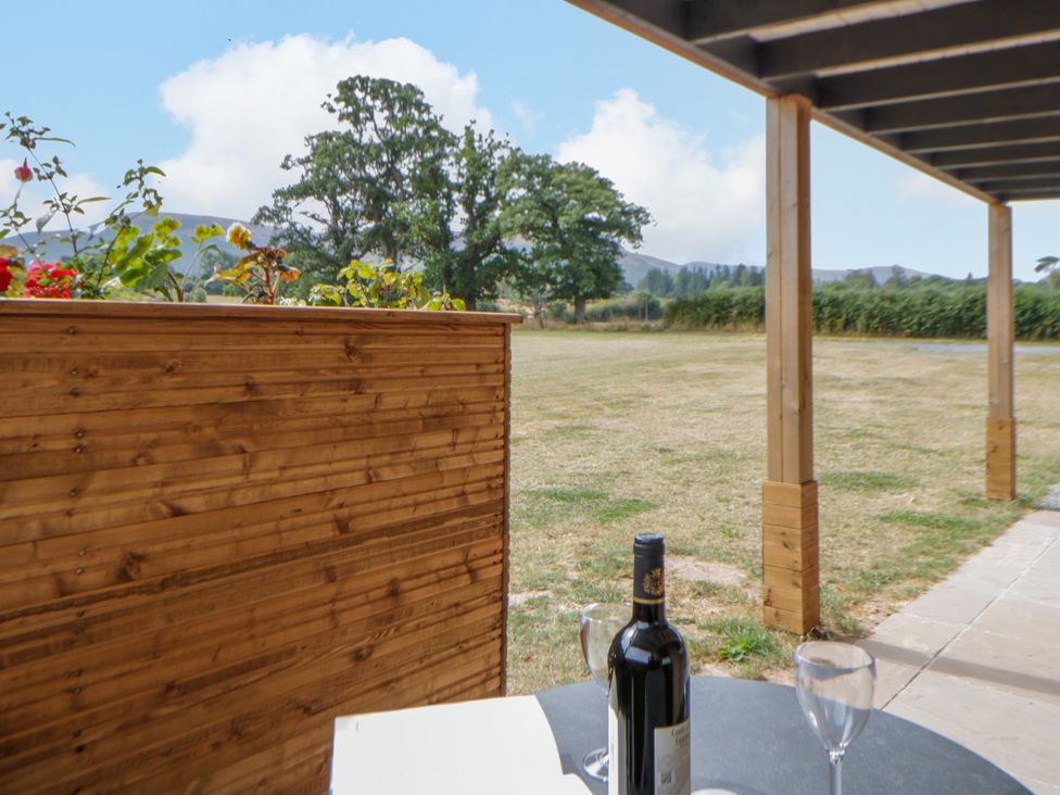 An outdoor area with a table, wine bottle and glasses at Oak Lodge in Brecon
