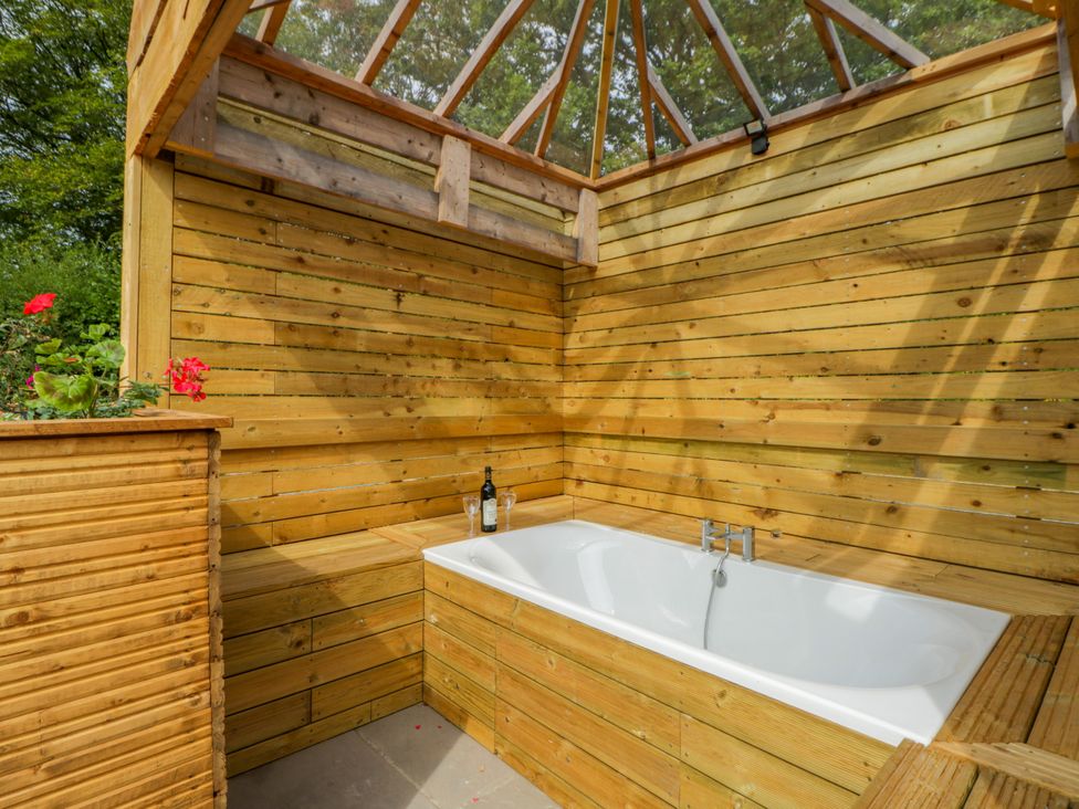 A bathtub and wooden walls in an outdoor bathroom at Oak Lodge Brecon