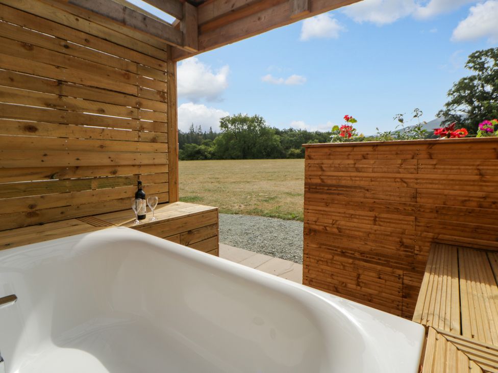 An outdoor bath area with a bathtub and wooden features at Oak Lodge Brecon