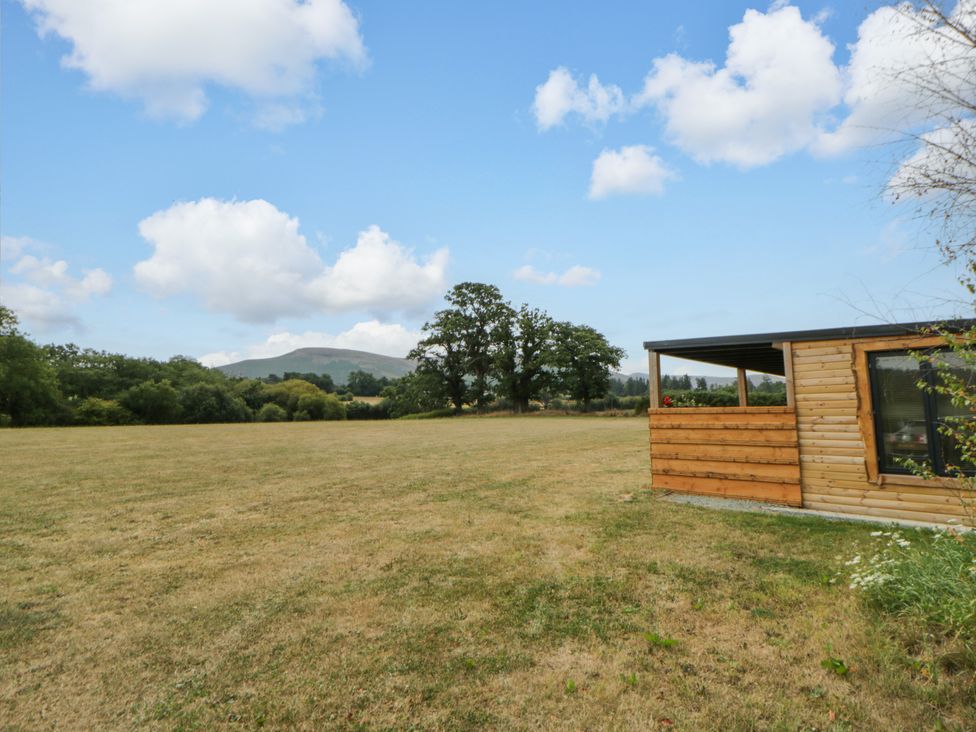A field with a wooden structure and trees at Oak Lodge in Brecon