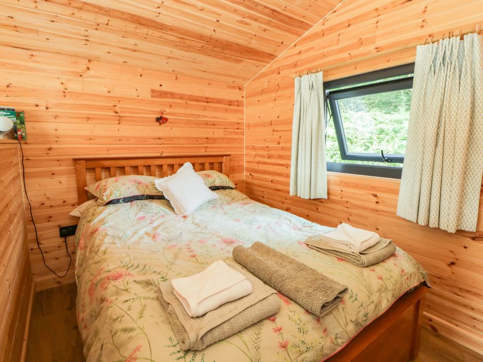 A bedroom with a bed and window at Sycamore Lodge in Brecon