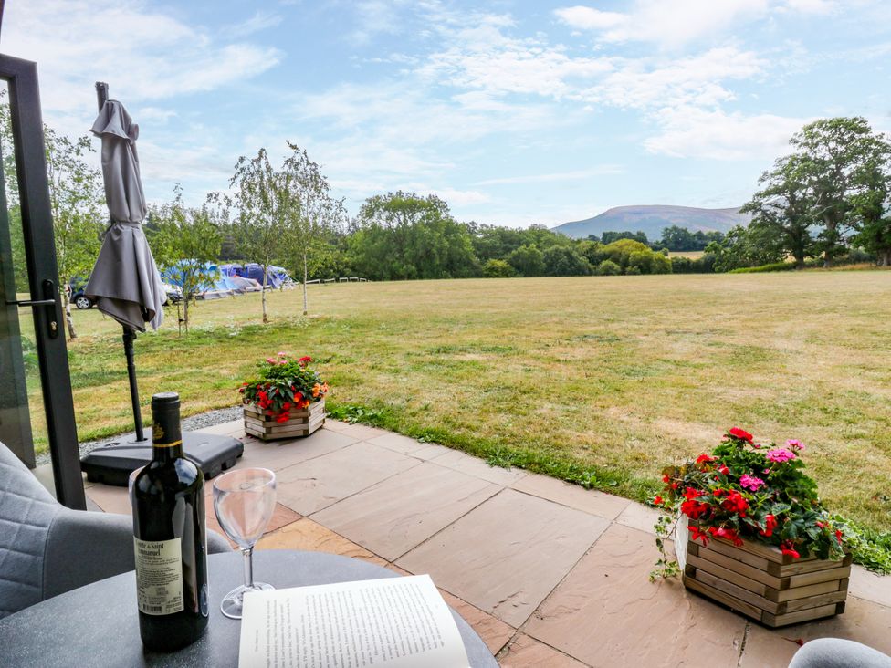 Outdoor seating area with a wine bottle and glass at Sycamore Lodge Brecon