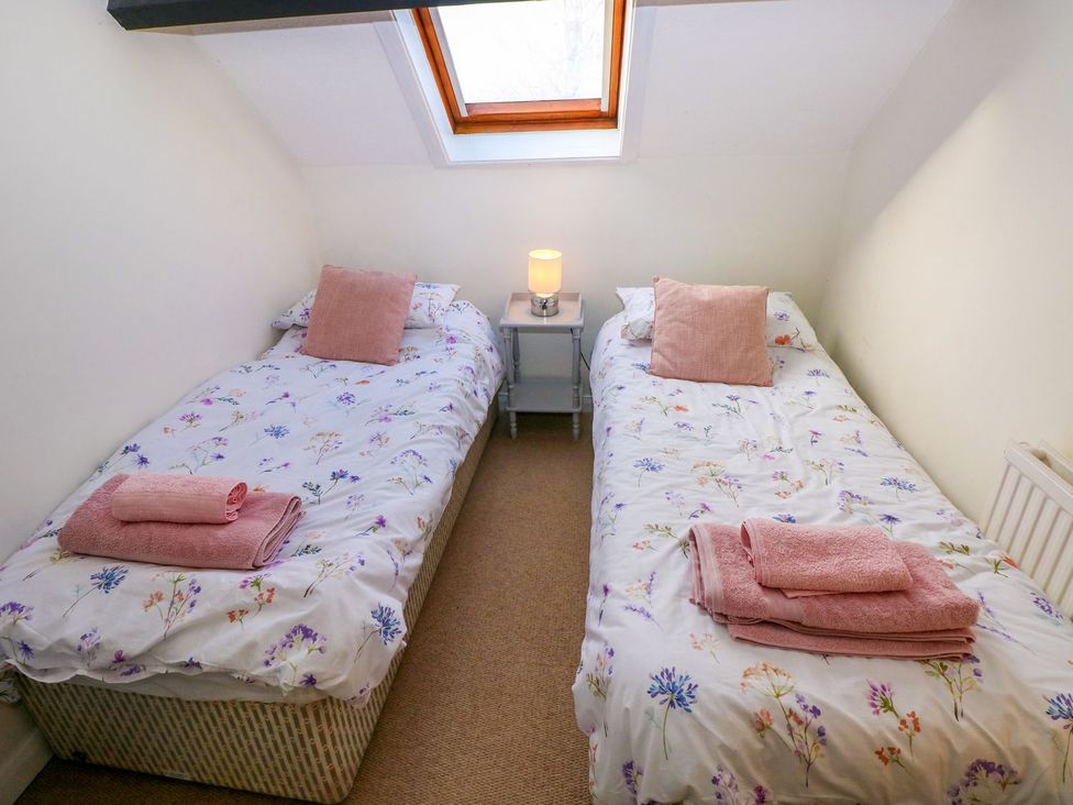 A bedroom with two single beds and a bedside table at The Stable in Haverfordwest