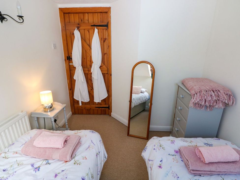 A bedroom with two beds and a mirror at The Stable in Haverfordwest