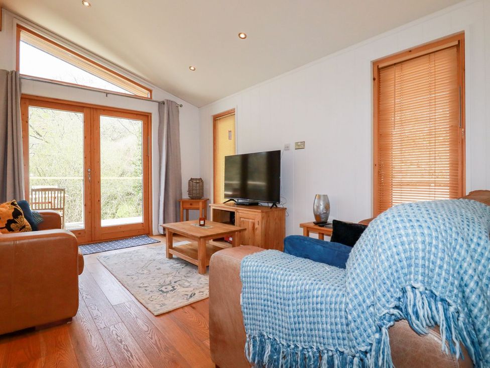 A living room with a sofa and television at 7 Stonerush Valley in Looe