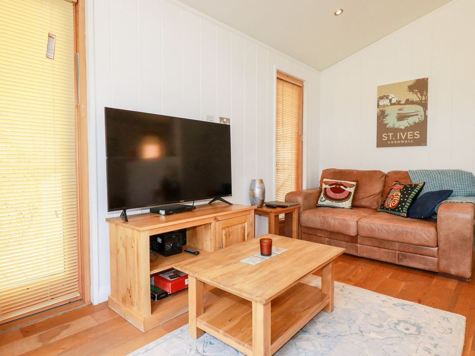 A living room with a television and sofa at 7 Stonerush Valley in Looe