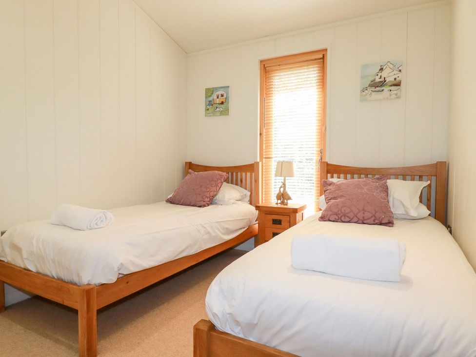 A bedroom with two single beds and a lamp on a nightstand at 7 Stonerush Valley in Looe