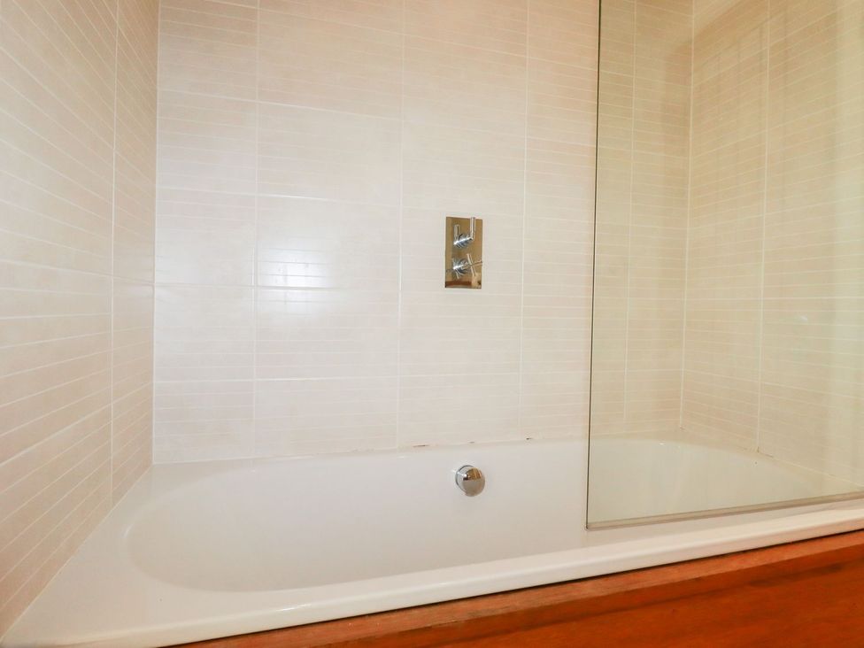 A bathtub with a shower and wall fixtures at 7 Stonerush Valley in Looe