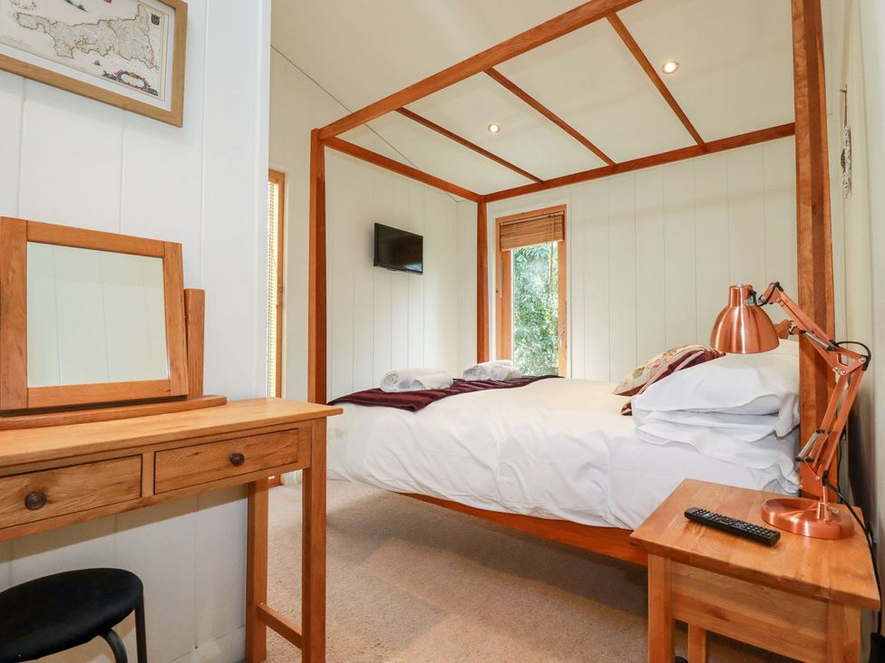 A bedroom with a four-poster bed and a dressing table at 7 Stonerush Valley Looe