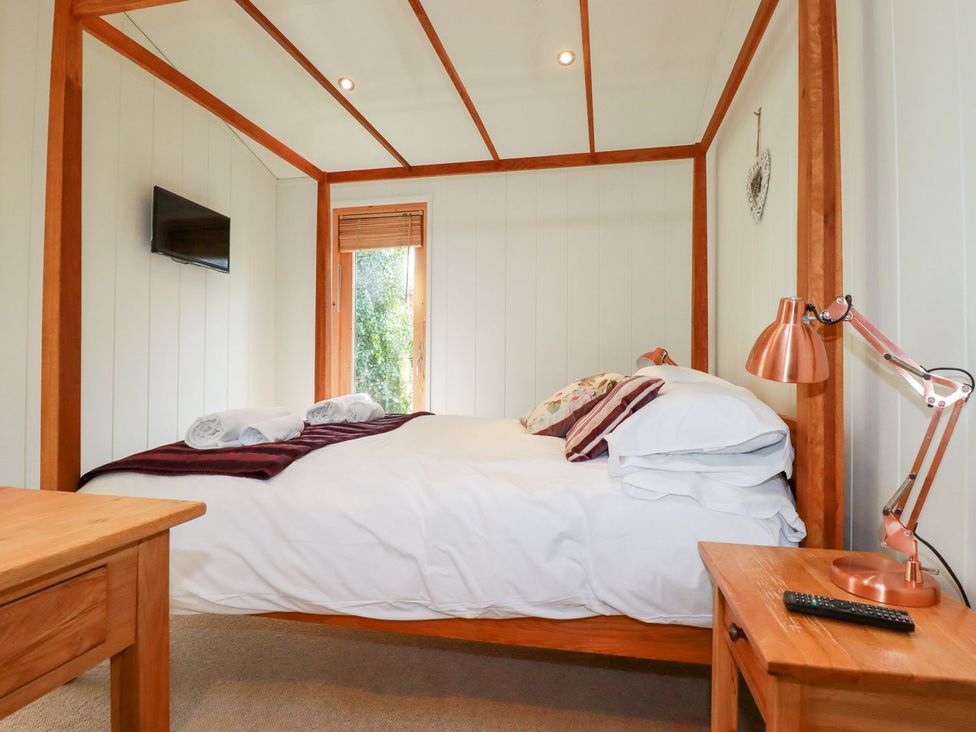 A bedroom with a four-poster bed and wooden furniture at 7 Stonerush Valley Looe