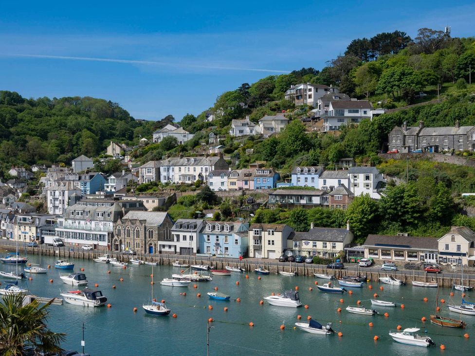 A coastal scene with boats and buildings along the water at 7 Stonerush Valley in Lanreath