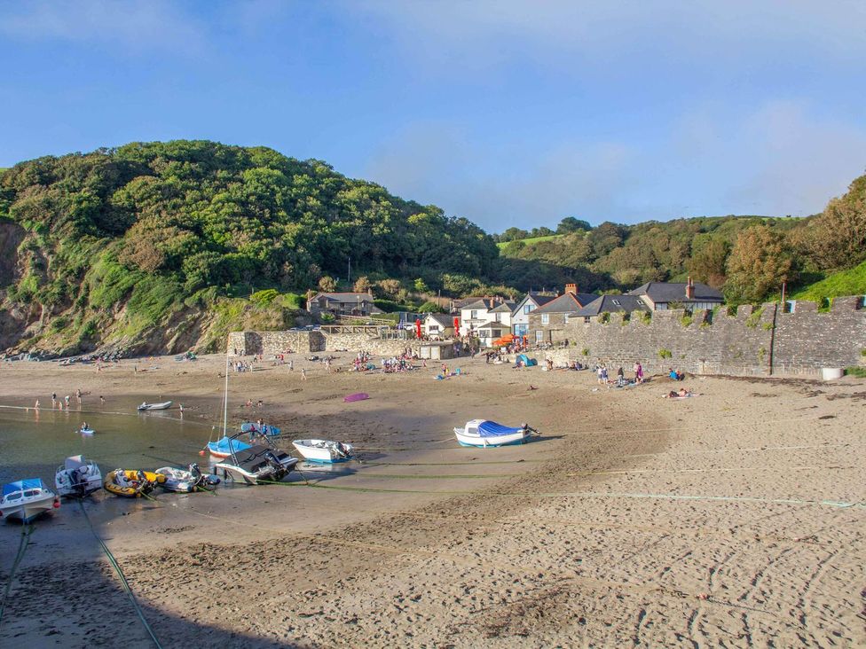 A beach area with boats and people near a wall at 7 Stonerush Valley in Lanreath