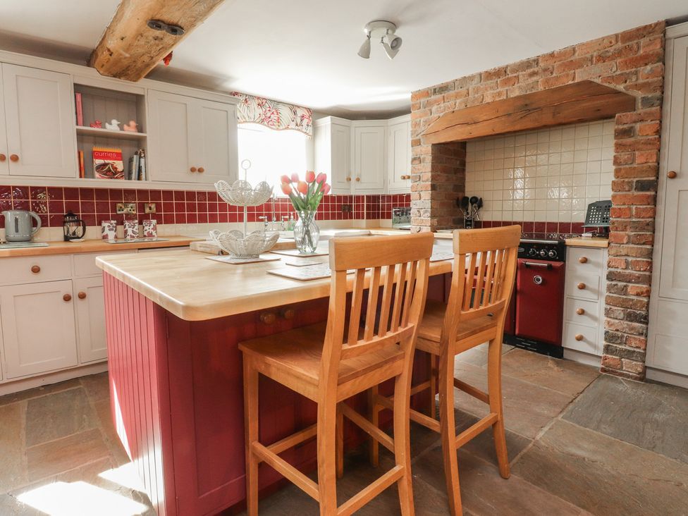 A kitchen with wooden bar stools and brick wall at The Shippon in Ormskirk