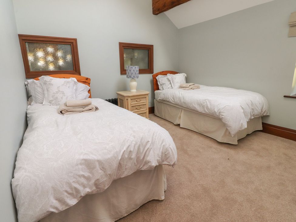 A bedroom with two beds and a bedside table at The Shippon in Ormskirk