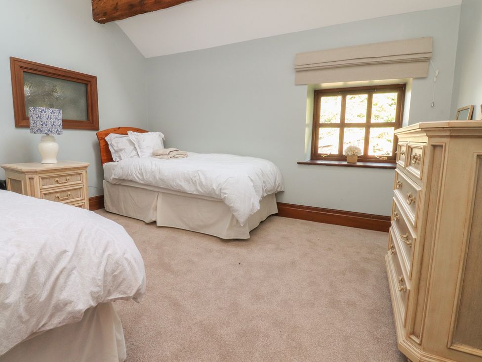 A bedroom with two beds, a dresser, and a window at The Shippon in Ormskirk