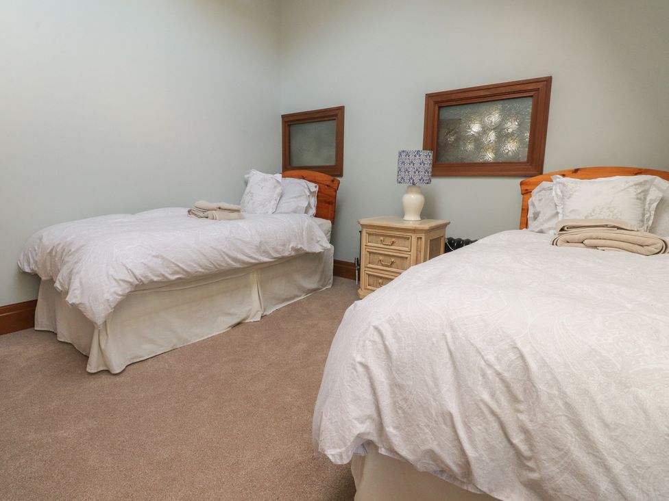 A bedroom with two beds and a nightstand at The Shippon in Ormskirk