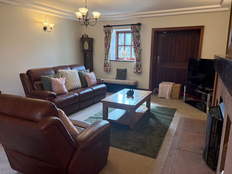 A living room with a sofa, armchair, coffee table and television at The Shippon in Burscough