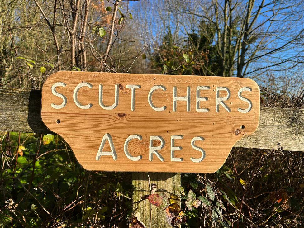 A wooden sign displaying Scutchers Acres outdoors