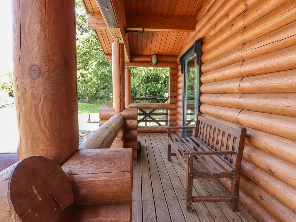 A porch with a wooden bench and log pillars at The Log Cabin in Ormskirk