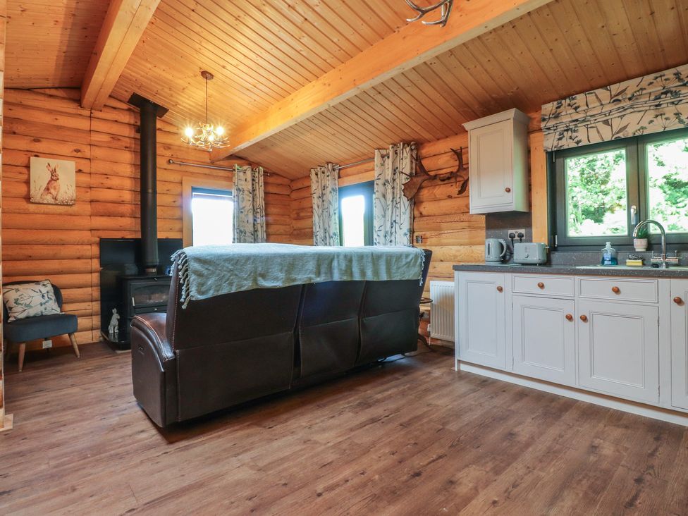 A living room with a sofa and kitchen area at The Log Cabin in Ormskirk