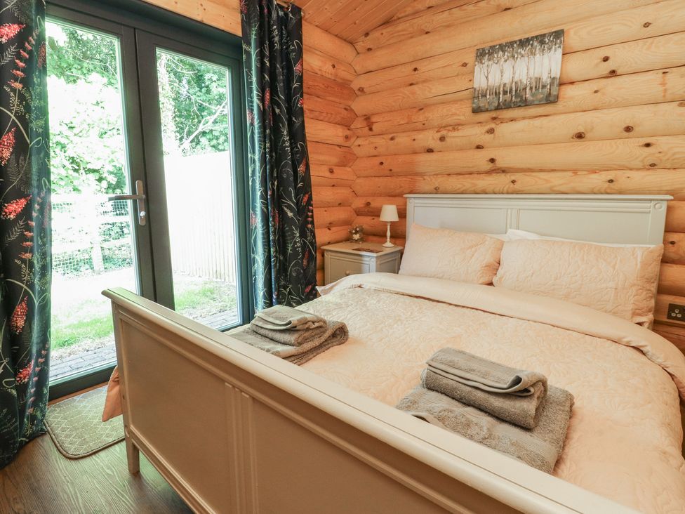 A bedroom with a bed and bedside table at The Log Cabin in Ormskirk