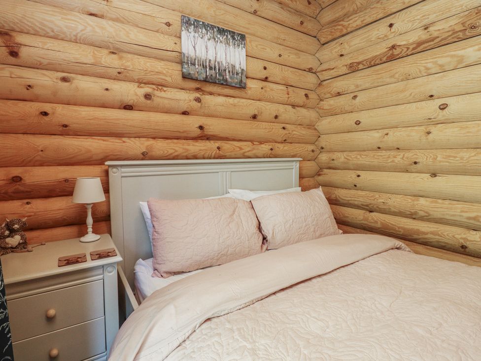 A bedroom with a bed and nightstand at The Log Cabin in Ormskirk