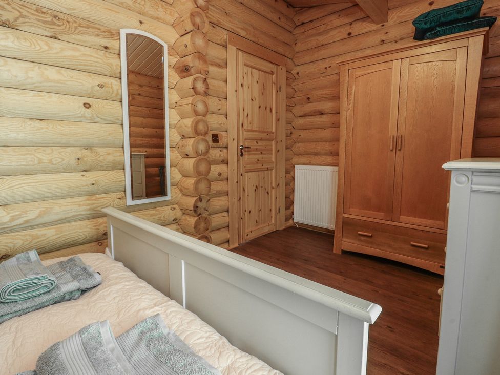 A bedroom with a bed and wardrobe at The Log Cabin in Ormskirk